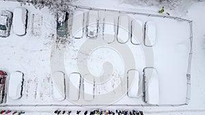 Aerila view of snow-covered cars stand in the parking lot on a winter day