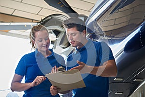 Aero Engineer And Apprentice Working On Helicopter In Hangar