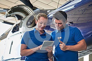 Aero Engineer And Apprentice Working On Helicopter In Hangar Loo