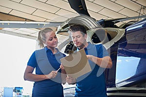 Aero Engineer And Apprentice Working On Helicopter In Hangar Loo