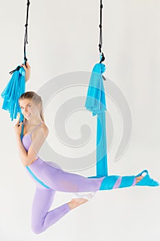 Aero fly yoga woman in sport uniform trainer stretching on blue hammock in white class