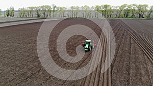 Aero. spring sunny day. On an agricultural, farming field, a tractor plows land, soil. Automated planting of potatoes on