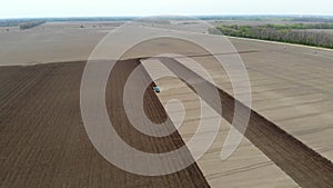 Aero. spring sunny day. On an agricultural, farming field, a tractor plows land, soil. Automated planting of potatoes on