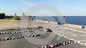 Aero, top view. Go-cart racing on circuit outdoors. There are safety barriers made of old wheels. Summer