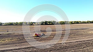 Aero video. Farm machinery Harvesting fresh organic potatoes in an agricultural field. coupled with a tractor, Red