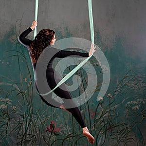 Aero yoga, a young woman doing yoga or stretching on a suspension,