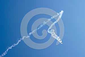 Aerobatic plane performing a multiple corkscrew maneuver leaving a smoke trail