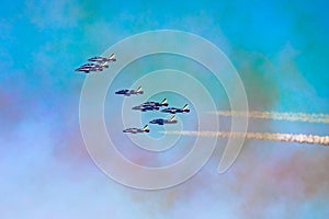 Aerobatic team in formation during aerobatic flight with smoke trails and multicolored sky