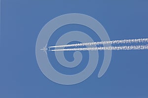 Aeroplane flying through clear blue sky with vapour trails