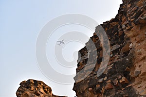 Aeroplane flying in sky above ancient ruins of Qutub minar in Delhi