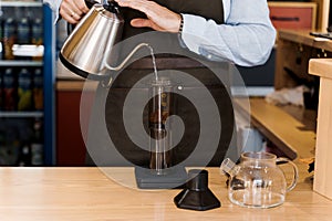 Aeropress coffee alternative making by barista in the cafe. Scandinavian coffee brewing method. Barista pours water to