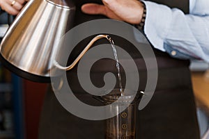 Aeropress coffee alternative making by barista in the cafe. Scandinavian coffee brewing method. Barista pours water to