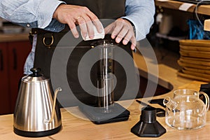 Aeropress coffee: barista spread ground coffee to pot. Alternative coffee brewing method. Handsome bearded barista makes