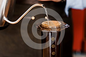 Aeropress coffee close up alternative making by barista in the cafe. Scandinavian coffee brewing method. Barista pours