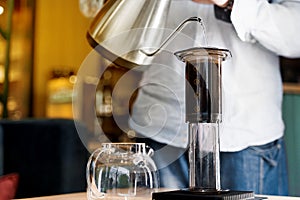 Aeropress coffee close up alternative making by barista in the cafe. Scandinavian coffee brewing method. Barista pours