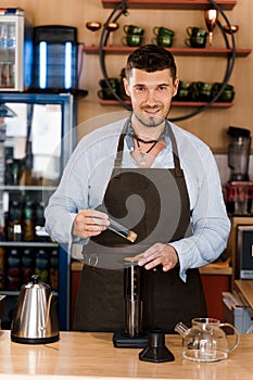 Aeropress coffee and handsome bearded barista in cafe. Barisa cook tasty coffee using alternative brewing method.