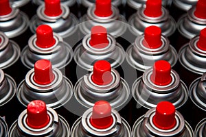 Aerosol cans with a bright red lid are in a row. Macro photo. Selective focus on the nozzle. paint