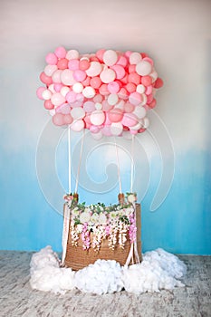 Aerostat from balloons with basket decorated with flowers. Balloons basket for air flight on background decorative blue sky with c