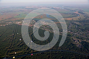 Aerostats in the air over fields and river.