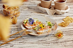 Aesthetic breakfast, lunch time with appetizer with smoked salmon, avocado, arugula, cucumber and edible flowers. Coffee