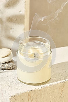 Aesthetic composition with aromatic candle in jar and smoke. Mockup soy wax candle in natural style with stone. Scented handmade