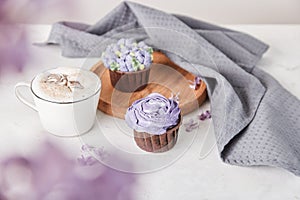 Aesthetic french dessert - cupcakes and coffee cup among lilac flowers. Guilty pleasure