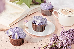 Aesthetic french purple floral cupcakes using trend Dreamy Escapism. Coffee time among lilac flowers, reading the book