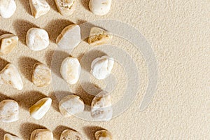 Aesthetic minimal pattern with pebble stones on fine sand background. Top view on natural stone neutral yellow beige