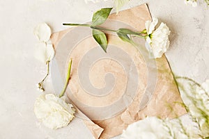 Aesthetic pastel beige crafting paper for text, template, invitation among white flowers top view. Copy space