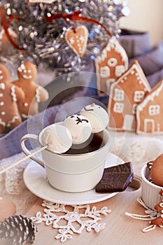 Aesthetic winter breakfast. Cute lying down marshmallow snowman in hot chocolate, gingerbread cookies. A cozy warm home