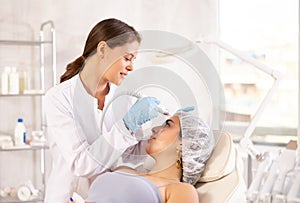 Aesthetician administering facial procedure on woman using ion bubble attachment