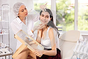 Aesthetician consulting young woman before facial skin treatments