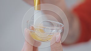 aesthetician stirring cream and serum in bowl, preparing rejuvenating cosmetic in beauty clinic, closeup