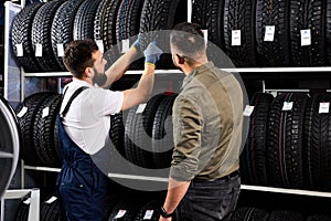 affable auto mechanic in uniform help customer with choice