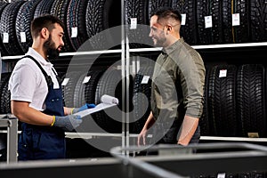 affable auto mechanic in uniform help customer with choice