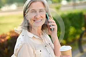 Affable smiling woman communicating by smartphone