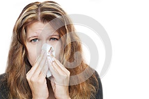 Affected by cold woman wipes her nose with handkerchief on white background