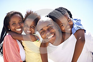 Affection brings them closer together. Two parents giving their children a piggyback while on the beach.