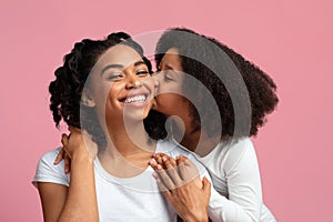 Affectionate Child. Little Black Girl Tenderly Kissing Happy Mom In Cheek
