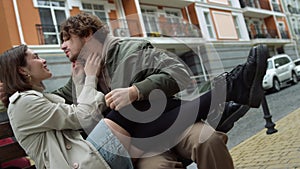 Affectionate couple caressing each other outdoor. Man holding woman legs on feet