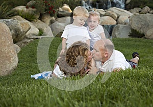 Affectionate Couple Kiss as Cute Twins Look On