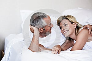 Affectionate couple looking at each other while relaxing on bed in bedroom