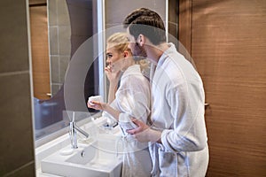 affectionate couple looking at mirror in white bathrobes