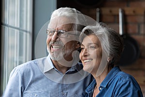 Affectionate elderly couple cuddle look away with happy white smiles