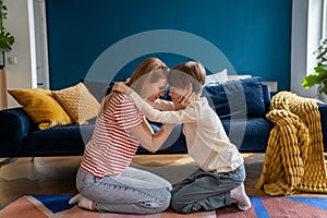 Affectionate empathic caring mom and teen son hug together sit on floor in living room at home.