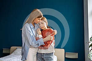 Affectionate empathic young mom tender embracing calming sad upset teen daughter.