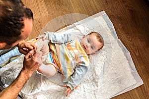 Affectionate father playing with his baby while he changes the disposable diaper