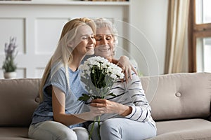 Affectionate grown up daughter cuddling aged mother congratulating with holiday