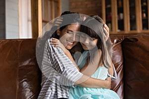 Affectionate latin mother and preteen girl cuddle with closed eyes