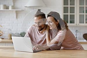 Affectionate loving millennial family couple using computer applications.